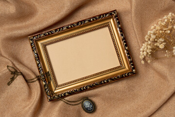 Empty frame with old medallion and flower on a fabric background from above. Vintage style. Top...