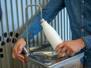 A young man filling his reusable bottle at an airport fountain