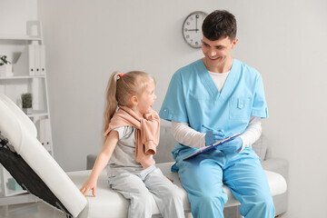 Male pediatrician with clipboard and little girl in clinic