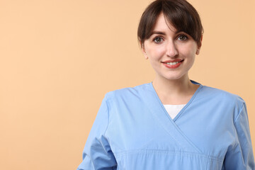 Fototapeta premium Portrait of smiling medical assistant on beige background. Space for text