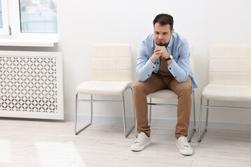 Man sitting on chair and waiting for appointment indoors