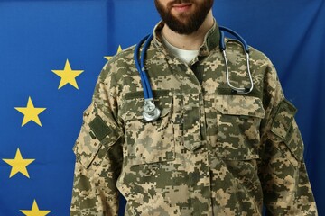 Man in military uniform with stethoscope against flag of European Union, closeup. Health care concept
