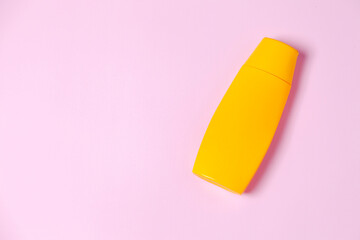 Yellow sunscreen bottle on pink background. Summer concept. Sunscreen concept. copy space.