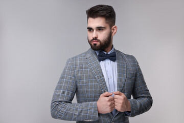 Portrait of handsome man in suit, shirt and bow tie on grey background. Space for text