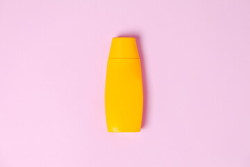 Yellow sunscreen bottle on pink background. Summer concept. Sunscreen concept. copy space.