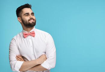 Portrait of smiling man in shirt and bow tie on light blue background. Space for text