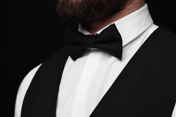 Man in shirt and bow tie on black background, closeup