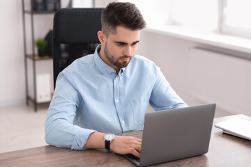 Fototapeta premium Young programmer working with laptop in office