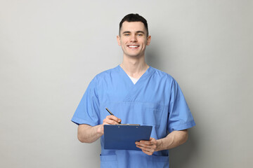 Portrait of smiling medical assistant with clipboard on grey background