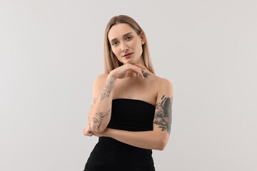 Portrait of beautiful tattooed woman on light background