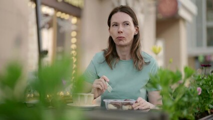 In a cozy outdoor cafe, a middle-aged woman enjoys dessert and coffee, forgetting about business and enjoying the morning tranquility.