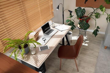 Teenager's workplace with laptop, books and alarm clock near window in room