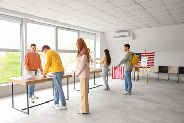 Voting young people near ballot boxes with USA flags at polling station