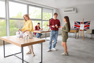 Voting young woman near ballot box with UK flag at polling station