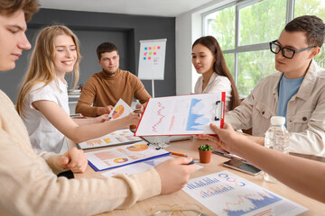 Young business people with diagrams working on marketing plan in office