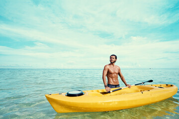 Hobby and vacation. Young man with the sea kayak  standing in water on ocean bay.