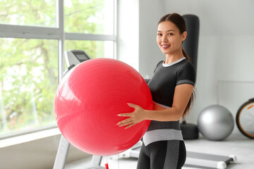 Sporty Asian woman with fitball in gym