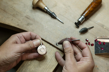 Stonesetter making a bezel set of the blue topaz stone on the silver pendant.