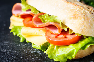 Sandwich with lettuce, cheese, tomatoes and ham. Healthy fast food, breakfast or lunch. Close up.