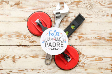 Tools and greeting card with text FELIZ DIA DEL PADRE on wooden background