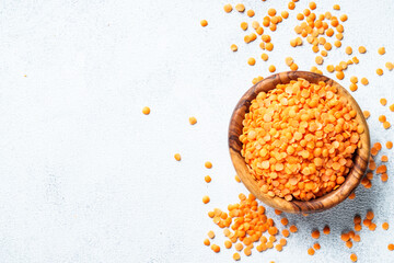Red lentils in wooden bowl on white background. Top view with copy space.