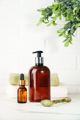 Natural cosmetic products in the bathroom on white background. Soap, serum bottle, jade roller.