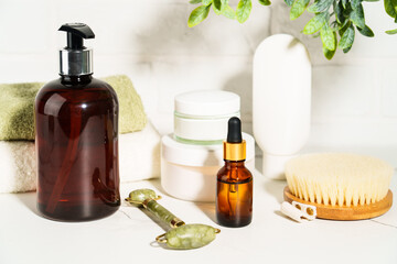 Bath background, beauty products in the bath shielf on white background. Cream, mask, soap, jade roller and face serum.