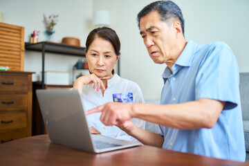 ネットショッピングでクレジットカード番号を打ち込むシニア夫婦