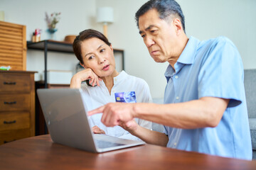 Obraz premium ネットショッピングでクレジットカード番号を打ち込むシニア夫婦