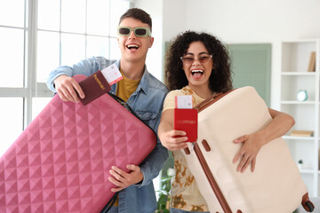 Happy young couple with suitcases, passports and tickets at home