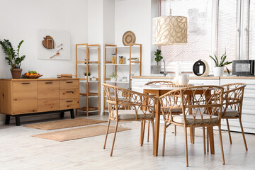 Dining table, chest of drawers, chairs and lamp in stylish kitchen