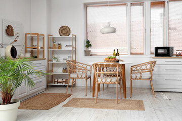 Interior of stylish kitchen with dining table, shelving unit, chairs and lamp