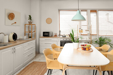 Interior of stylish kitchen with dining table, chairs and lamp