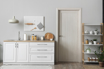 Interior of beautiful kitchen with white counters, door, shelving unit and lamp