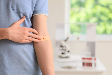 Male blood donor with applied medical patch in clinic, closeup