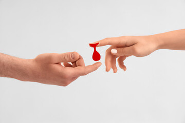 Female blood donor giving paper drop to man on light background