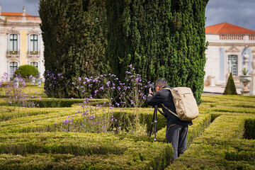 A travel photographer takes pictures of a local landmark in Lisbon with a camera tripod.