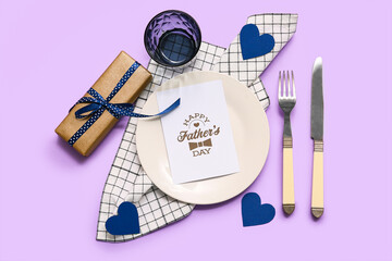Stylish table setting with greeting card and gift box on lilac background. Father day celebration...