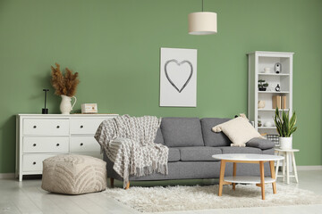 Modern interior of living room with cozy sofa, coffee table and shelving unit