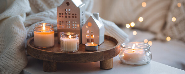 Winter home aromatherapy, cozy atmosphere. Burning aroma candles on wooden tray, knitted blanket,...