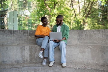 Interested focused african american students girl and guy sits with laptop near university library...