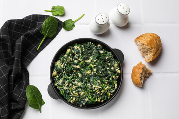 Tasty spinach dip with eggs in dish served on white tiled table, flat lay