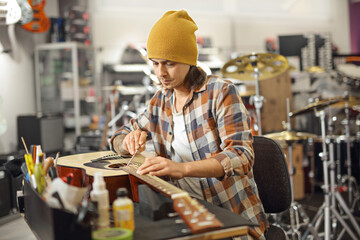 Young man fixing an acoustic guitar