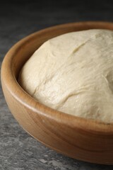 Raw dough in bowl on grey table, closeup