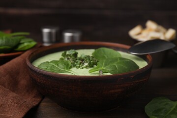 Delicious spinach cream soup served on wooden table, closeup