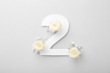 Paper number 2 and beautiful flowers on light grey background, top view