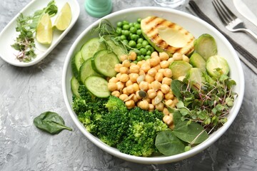 Healthy meal. Tasty vegetables and chickpeas in bowl on grey table