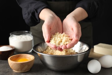 Woman with shortcrust pastry at grey table, closeup