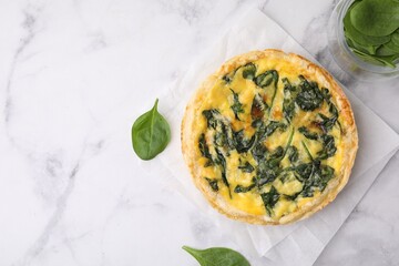 Delicious pie with spinach on white marble table, flat lay. Space for text