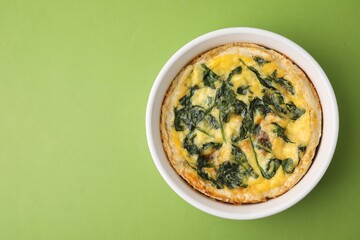 Delicious pie with spinach on green background, top view. Space for text